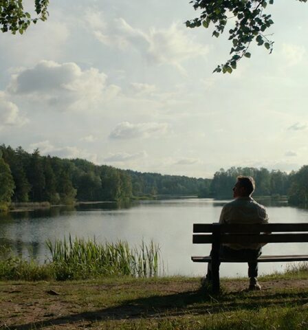 A lone Swedish man on a bench by a lake