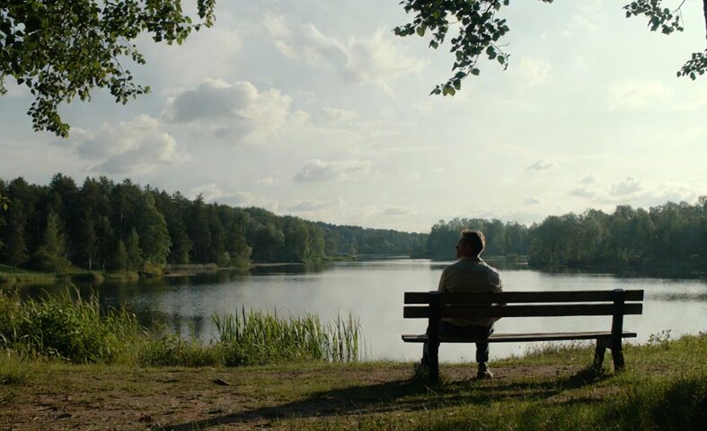 A lone Swedish man on a bench by a lake