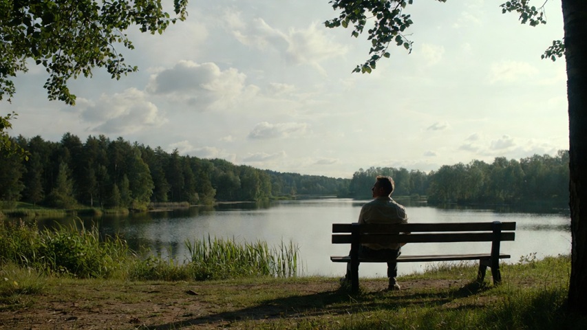 A lone Swedish man on a bench by a lake